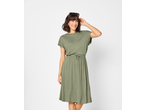 Mulher com vestido verde-oliva, sorrindo e olhando para o lado.