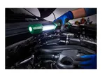 Person in blue gloves using a green work light to inspect a car engine.