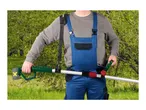 Man in overalls using a long-reach hedge trimmer with a battery pack, outdoors in a garden.