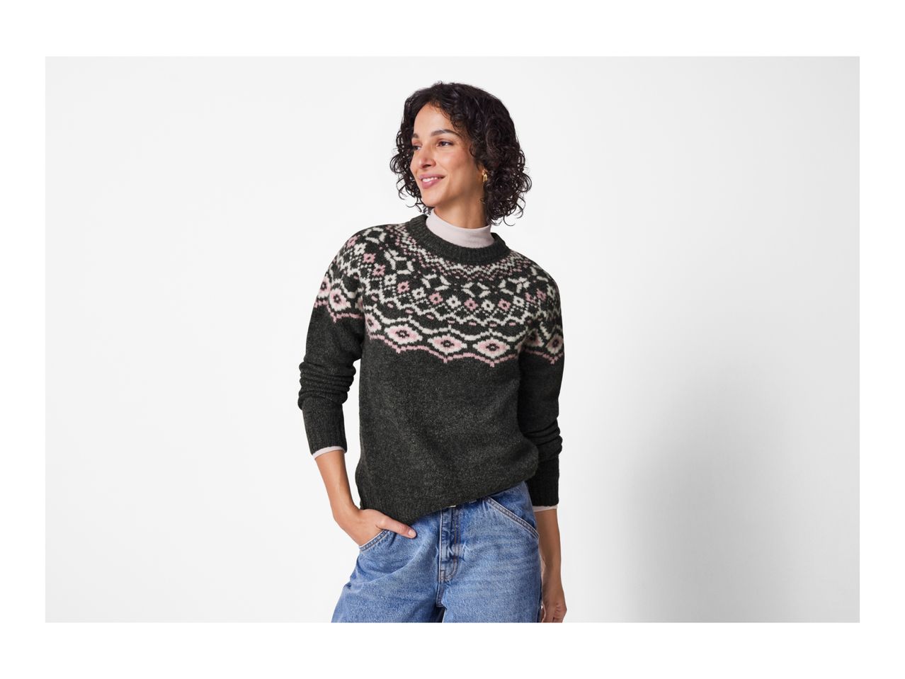 Woman in a dark gray fair isle sweater and blue jeans.