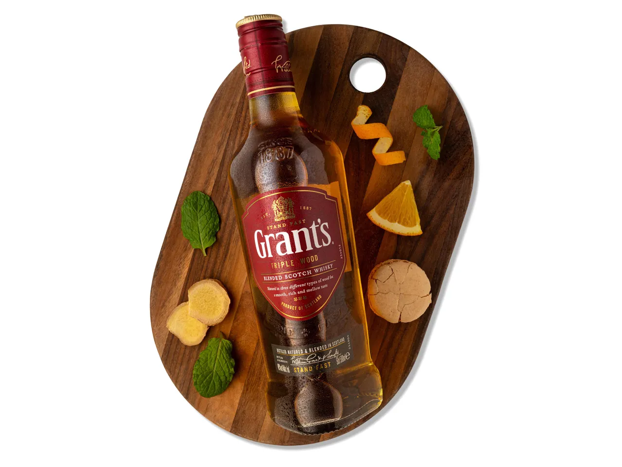 Grant's Triple Wood skót whisky palack gyömbérrel, naranccsal és mentával fa táblán.