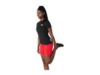Woman in black short-sleeved top and red shorts stretching her leg.