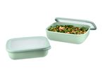 Two light green food containers, one filled with a kale, chickpea, and walnut salad.