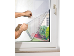 Bărbat aplicând folie de fereastră PARKSIDE cu o spatulă pe un geam.