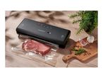SilverCrest vacuum sealer with a vacuum-sealed piece of meat, garlic, rosemary, and peppercorns on a wooden board.