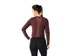 Femme vue de dos portant un haut bordeaux à manches longues et des leggings noirs.