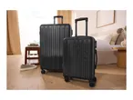 Two black suitcases, one large and one small, in a bedroom setting.