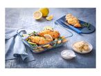 Baked chicken and vegetables in a glass dish with lemons, salt, and cheese.
