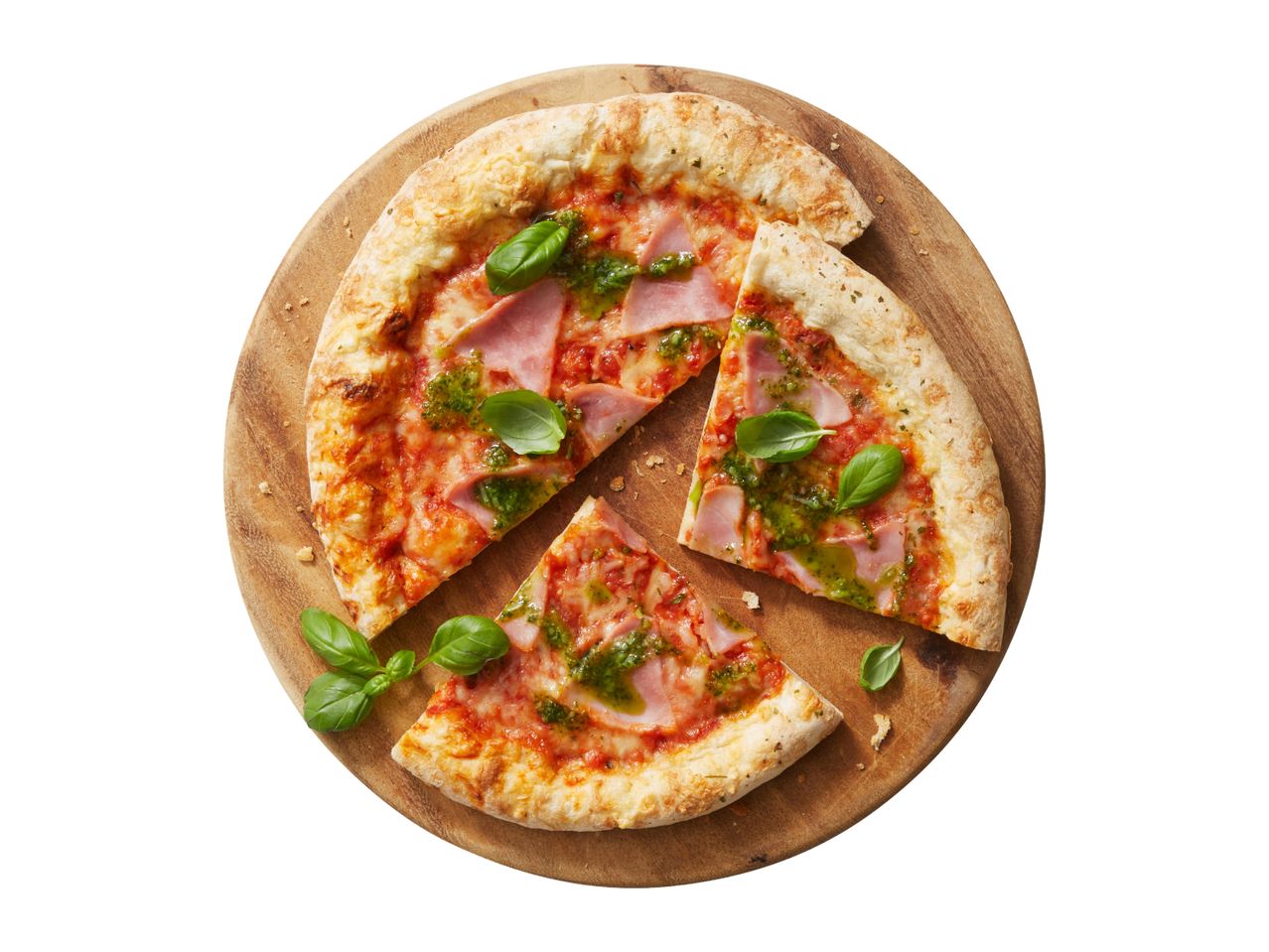 Pizza with ham, pesto, and basil on a wooden board, with two slices cut out.