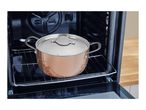 Copper pot with lid inside an open oven