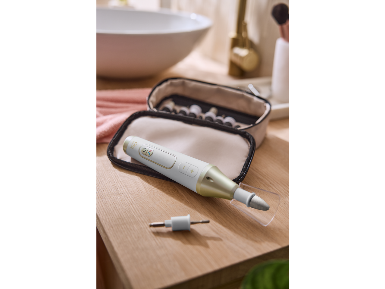 Electric manicure/pedicure device with attachments and case on a wooden surface.