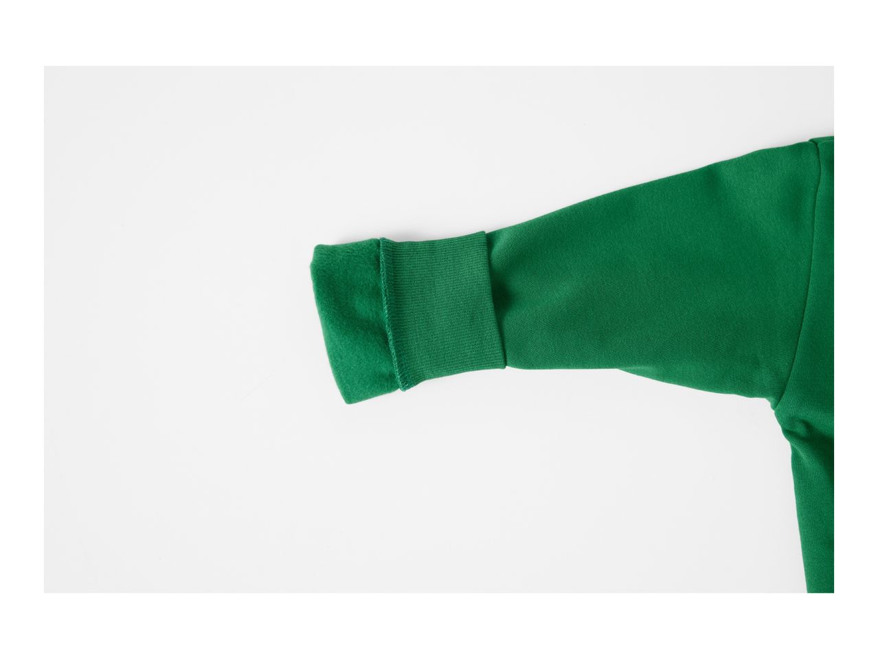 Close-up of a green sweatshirt sleeve with a ribbed cuff on a white background.