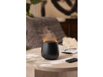 Black aroma diffuser with flame effect and remote control on a side table.