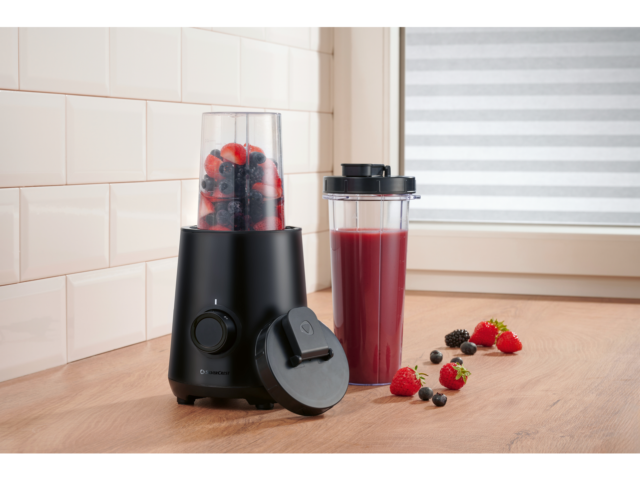 SILVERCREST blender za smoothie s bobičastim voćem i gotovim smoothiejem na drvenoj radnoj ploči.