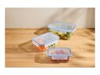 Three glass food storage containers with blue lids, filled with fresh vegetables and salad.