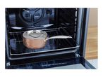 Copper saucepan with lid on an oven rack inside a black oven