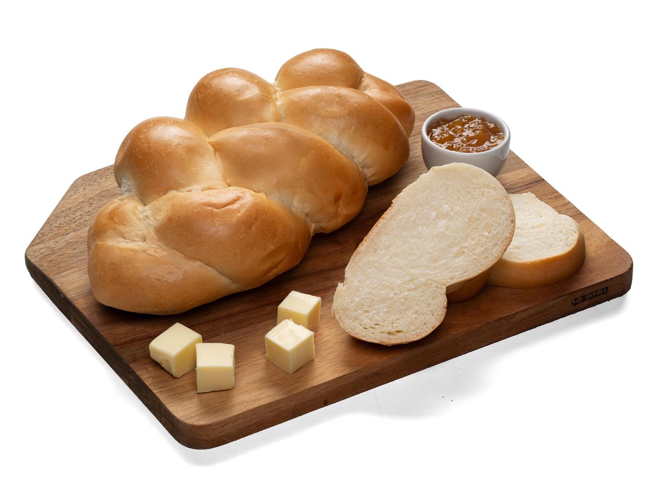 Fonott kalács, szeletelt kenyér, vajkockák és lekvár egy fa vágódeszkán.