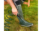 Homem a limpar uma bota de borracha verde com uma mangueira espiral PARKSIDE na relva.