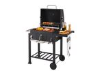 Black charcoal grill with food cooking on the grates and grilling accessories on the side.