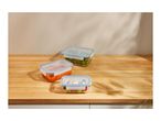 Three glass food storage containers with different foods on a wooden counter.