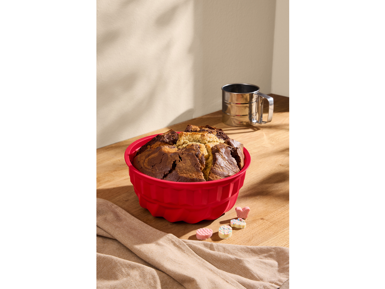 SILVERCREST® kalup za pečenje sa mramornim kolačem i ukrasima na drvenom stolu.