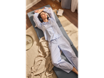Woman relaxes on a comfortable foldable mattress listening to music with headphones.