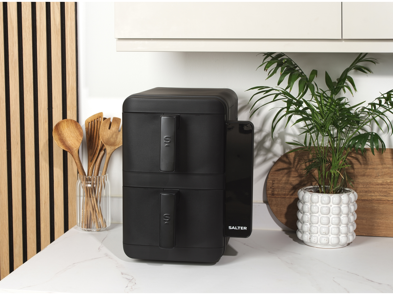 Salter VertiCook Air Fryer 10L on a kitchen counter with wooden utensils and a plant.