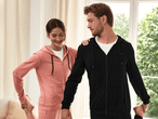 Ein Mann und eine Frau in Sportbekleidung dehnen sich in einem hellen Raum.