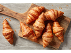 Croissants au beurre frais et dorés sur une planche à découper en bois.