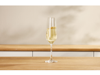 Taça de champanhe com bolhas numa mesa de madeira, com fundo claro