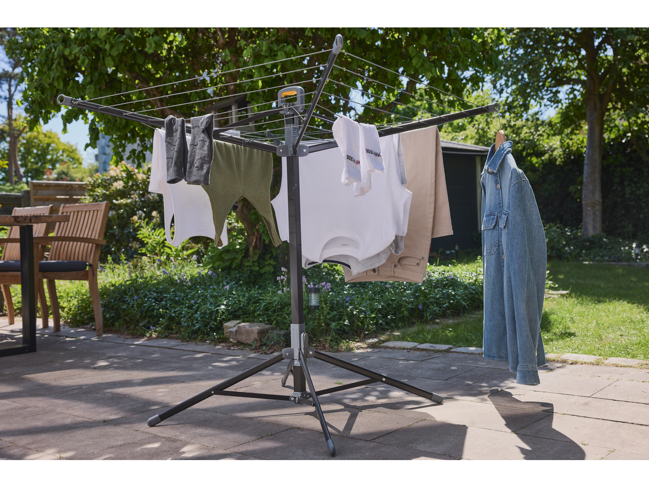 Clothes drying rack with various garments, including shirts, pants, and a denim jacket, outdoors.