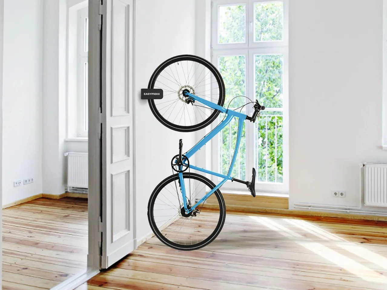 Una bicicletta blu è appesa verticalmente a una parete bianca con un supporto EASYmaxx.