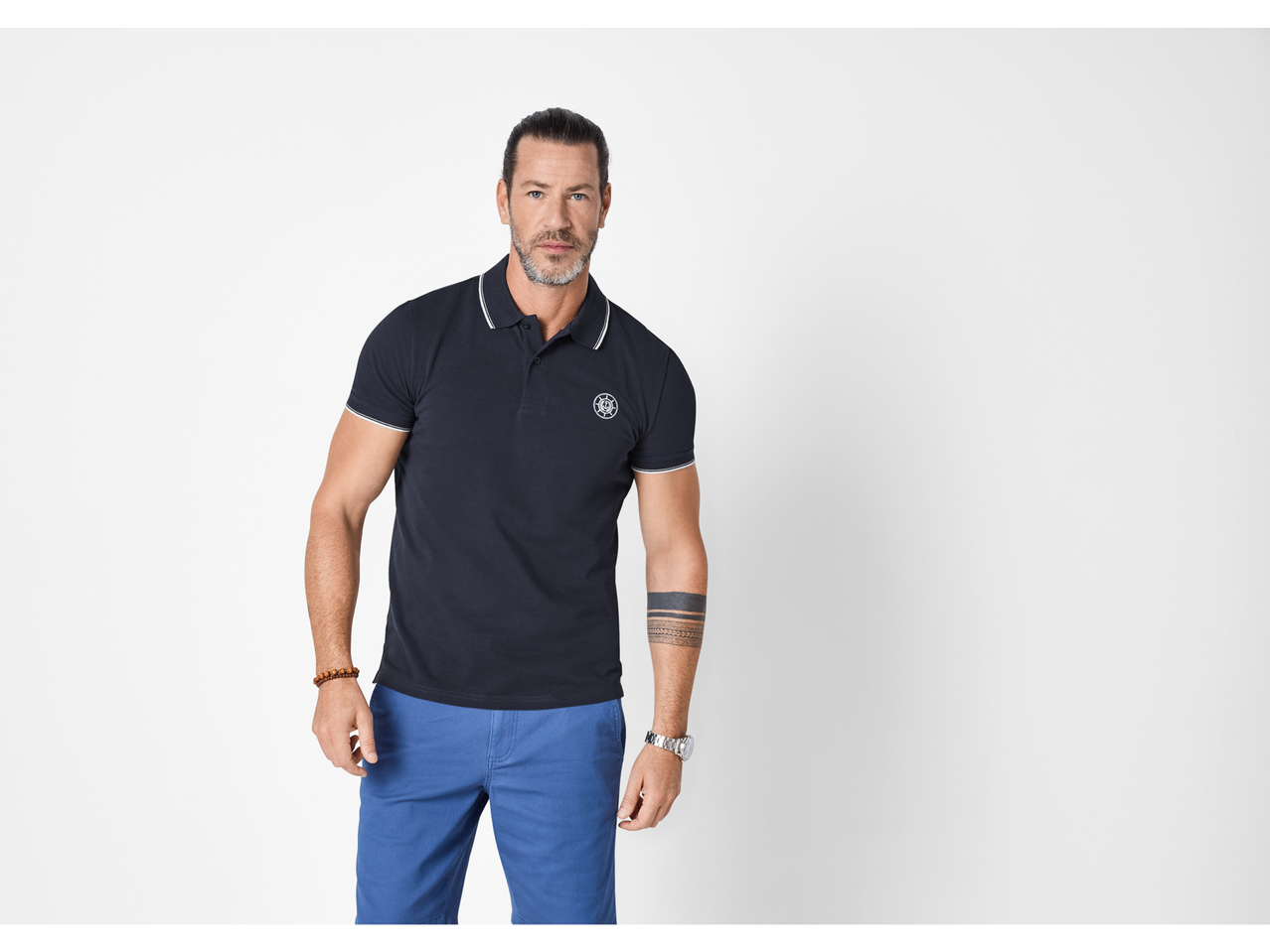 Muškarac u tamnoplavoj polo majici s bijelim detaljima i plavim kratkim hlačama.