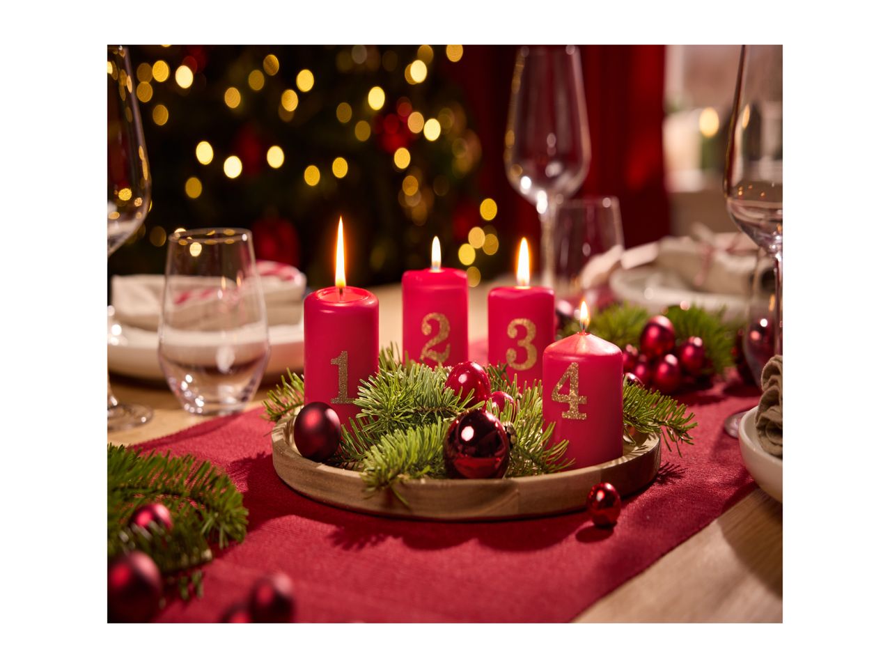 Advent wreath with four lit red candles, numbered 1 to 4, on a festive table.