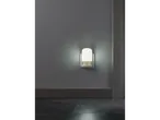 A white night light plugged into a wall outlet, illuminating a dark room.