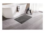 A modern bathroom with a white freestanding bathtub, a gray bath mat, and a small black stool.