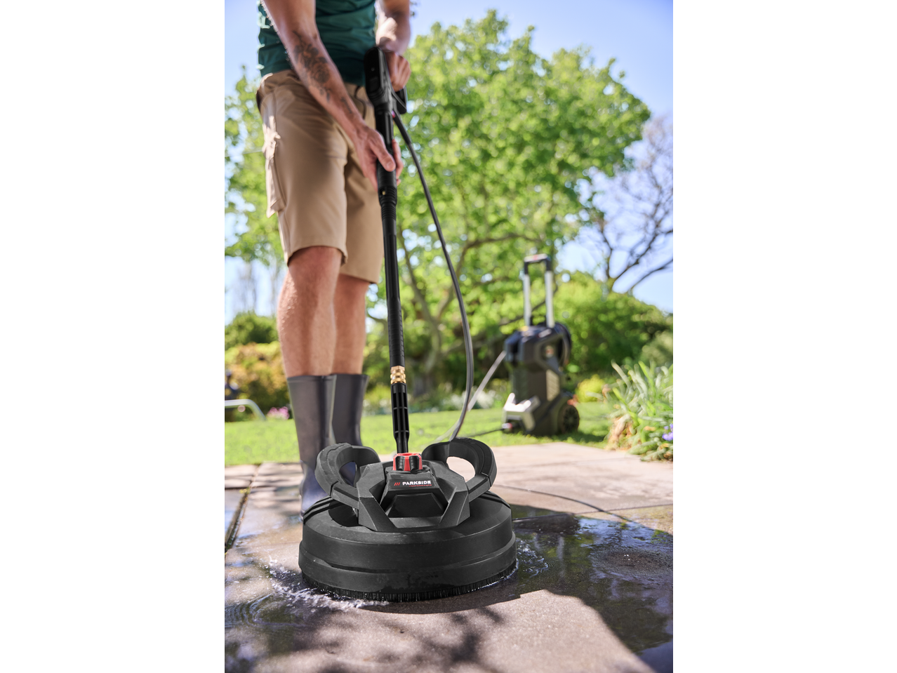 Homem a limpar o pátio com uma máquina de lavar à pressão Parkside Performance®.