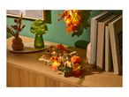 Autumnal home decor with a green mushroom lamp, candles, pumpkins, and books on a wooden cabinet.