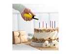 Hand lighting colorful candles on a birthday cake with sprinkles, next to a wrapped gift.