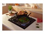A roasted chicken and vegetables cooking in pans on a gas stove in a festive kitchen.