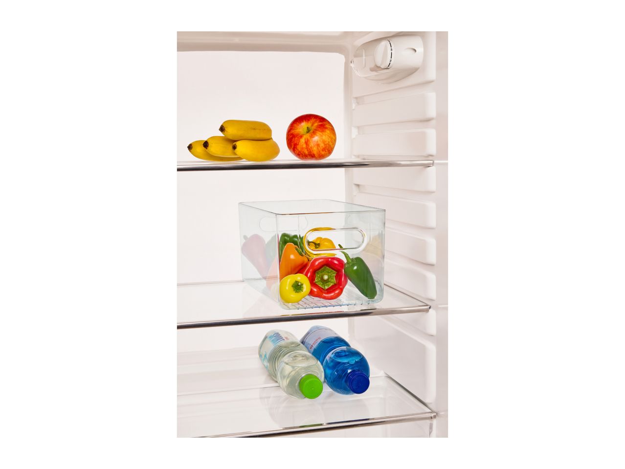 Open refrigerator with bananas, an apple, bell peppers in a container, and water bottles.