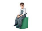 Smiling child in waterproof overalls and boots, sitting on a green cylinder.