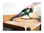 A person uses a cordless handheld vacuum cleaner to clean sawdust from a wooden workbench.