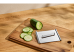 Ralador multifuncional SILVERCREST com pepino e rodelas de pepino numa tábua de madeira.
