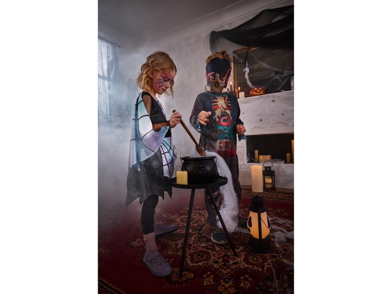 Two children in Halloween costumes stirring a cauldron in a spooky, smoke-filled room.