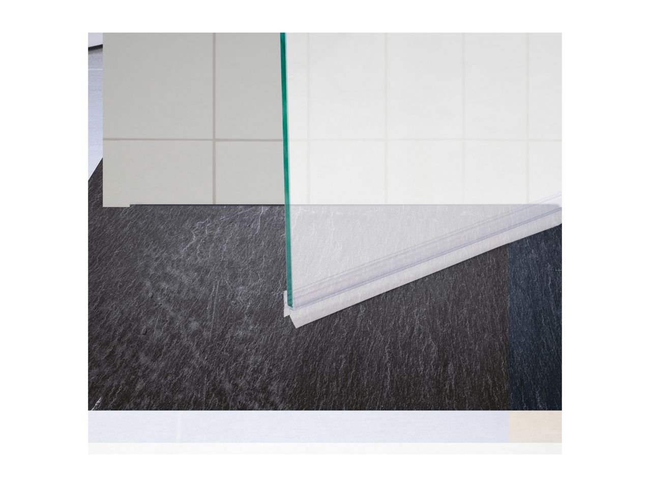 Shower screen with a clear seal on a dark tiled floor.