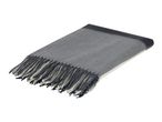 Folded grey and white throw blanket with fringe