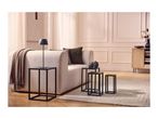 Modern living room with a beige sofa, black side tables, a lamp, and a textured rug.