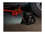 A work light illuminates a red car jack under a car, highlighting auto repair tools.