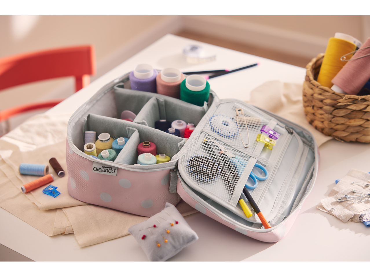 Atvira rožinė taškuota Crelando® siuvimo reikmenų rankinė, pilna siūlų ir siuvimo priemonių.